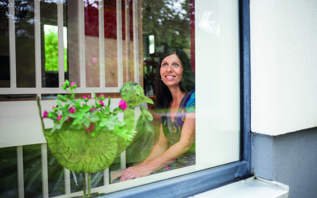 Energetische Modernisierung: glückliche Frau hinter einem Fenster
