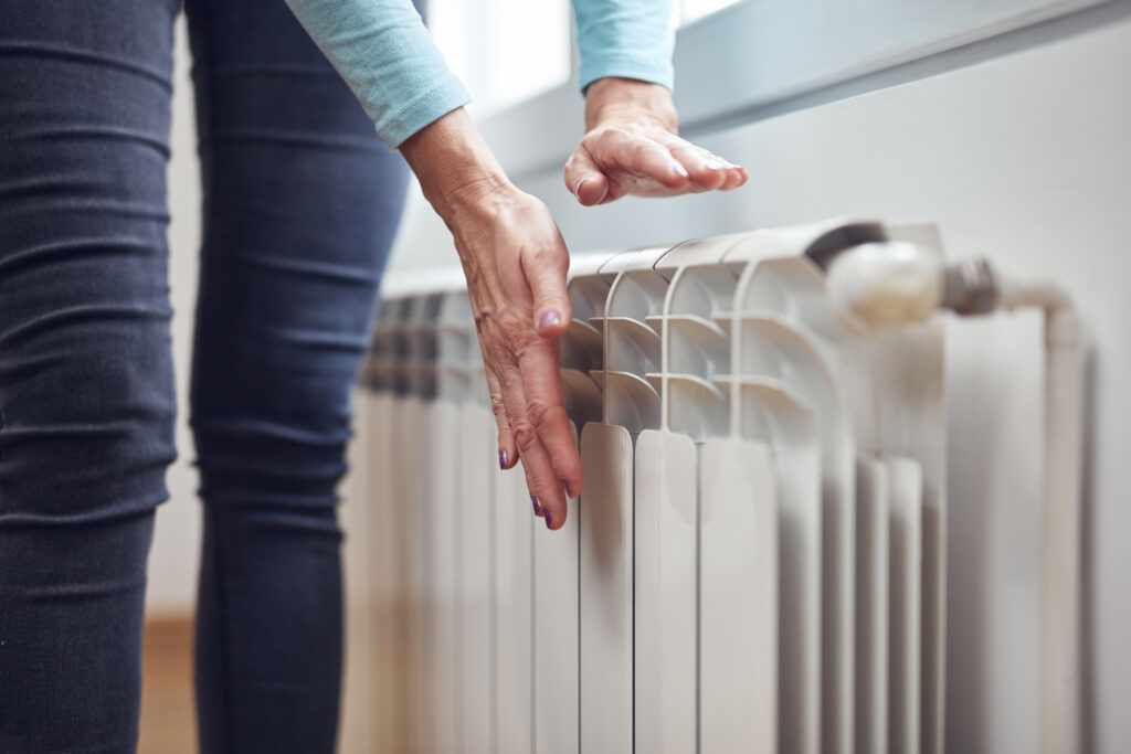Frau überprüft die Wärme bei der Heizung: Energie im Heizungskeller sparen