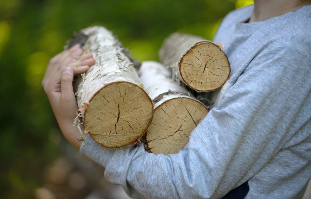 Frau trägt Holz: Den Kamin richtig nutzen