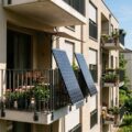 Balkonkraftwerk: zwei Solarmodule sind außen am Balkongeländer eines Mehrfamilienhauses in die Sonne ausgerichtet